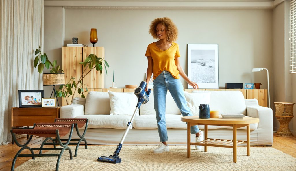 Woman cleaning carpet with vacuum cleaner at home